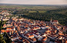 Luftaufnahme der Stadt Znaim mit roten Dächern und umliegender Landschaft.